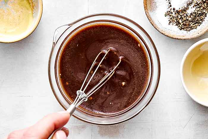 Whisking balsamic vinaigrette in a bowl.