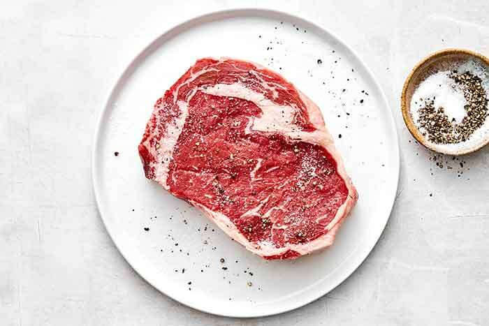 Seasoning steak with salt and pepper.