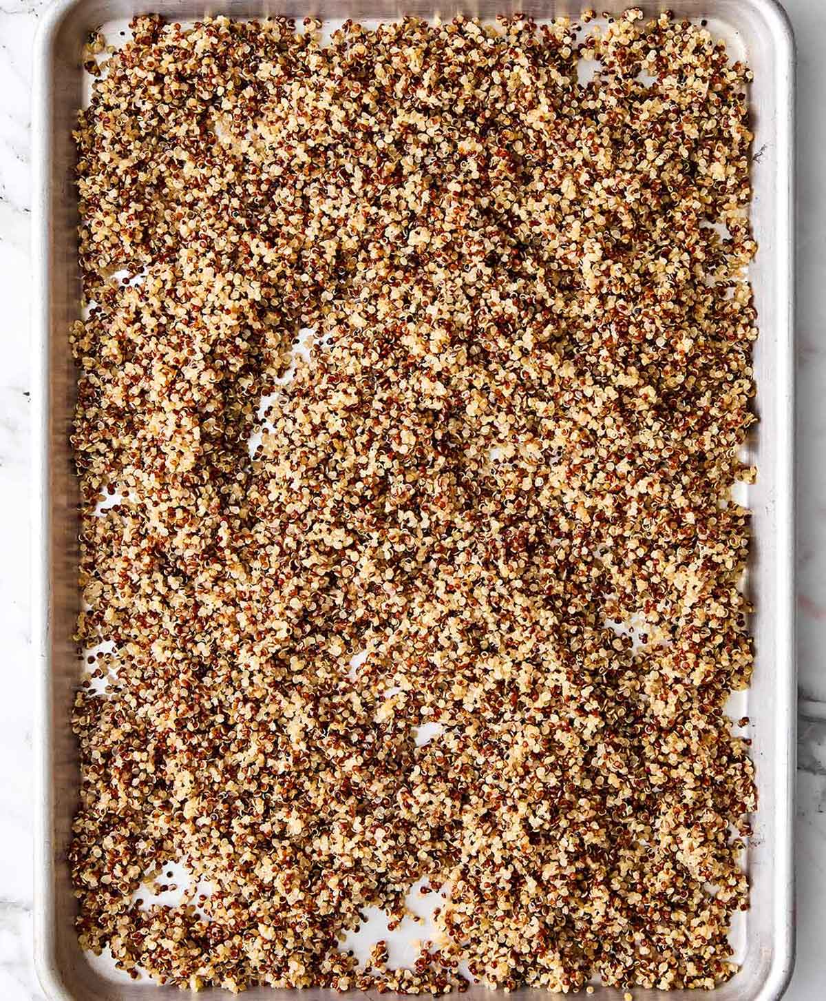 This is the Mediterranean quinoa salad I always make! It hits the perfect balance of fresh, briny, and satisfying...and it hold up well. Cooling cooked quinoa on a baking sheet.
