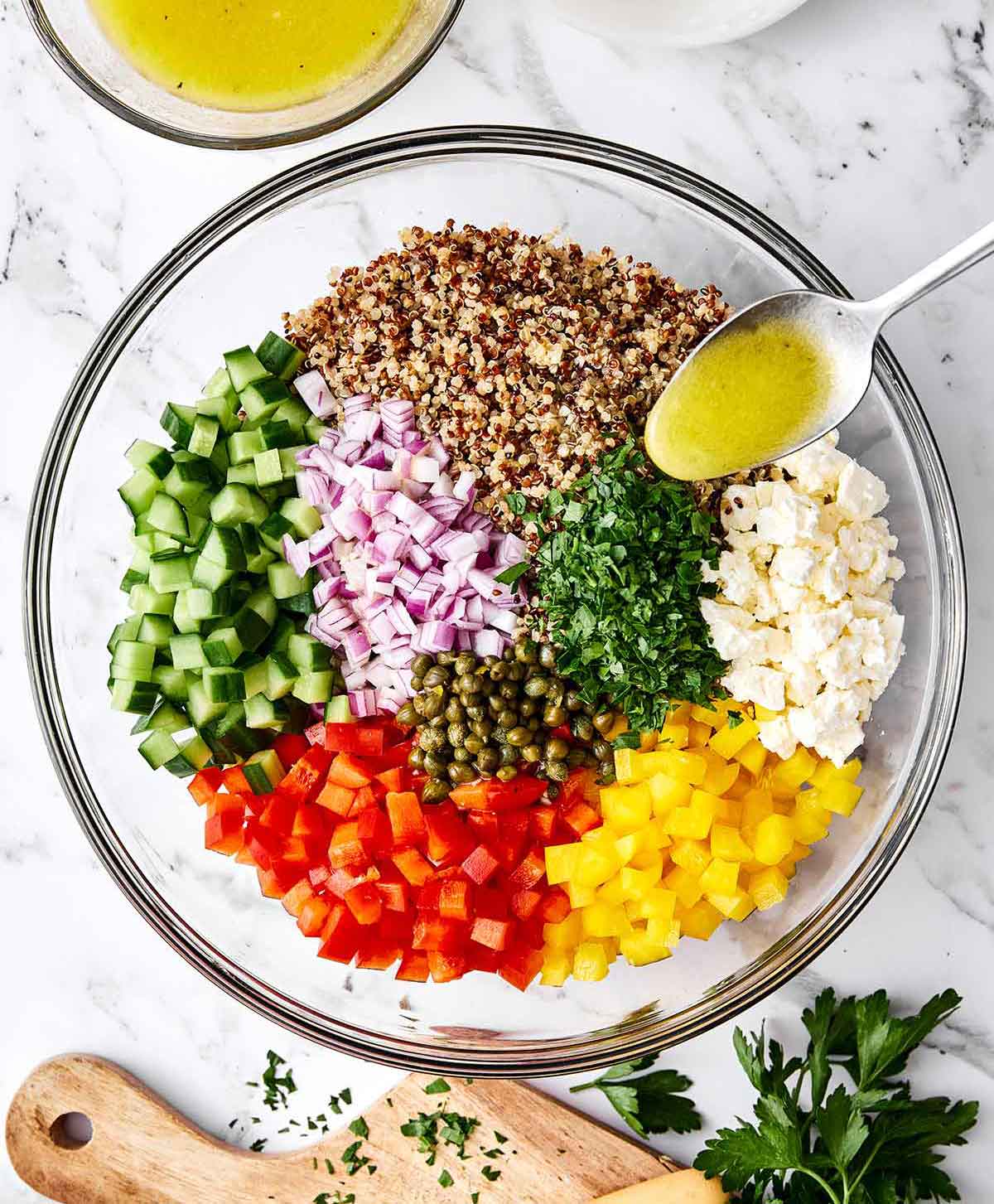 This is the Mediterranean quinoa salad I always make! It hits the perfect balance of fresh, briny, and satisfying...and it hold up well. Mixing quinoa salad in a bowl.
