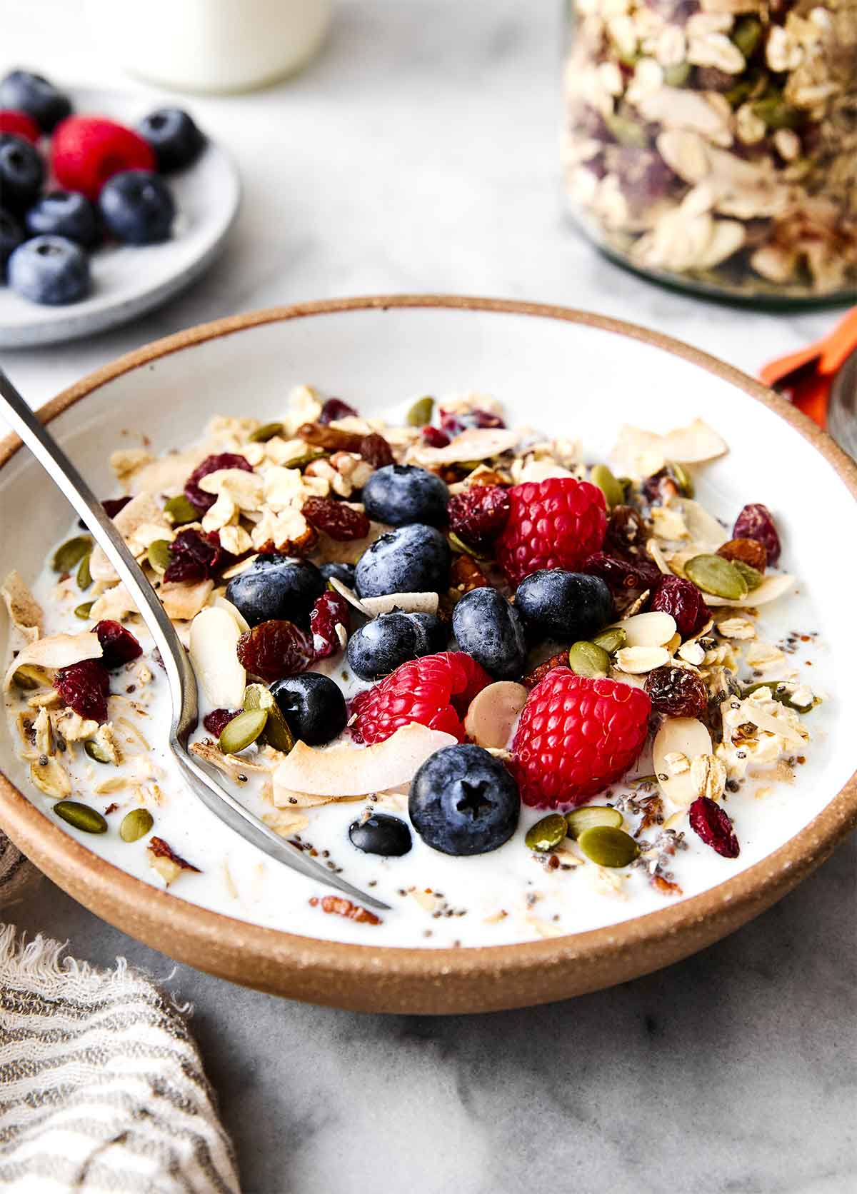 A bowl of muesli with milk and fruits.
