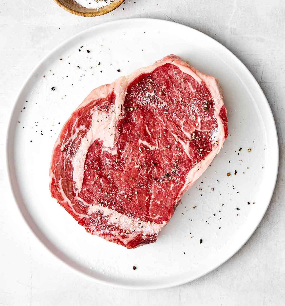 Seasoning steak with salt and pepper.