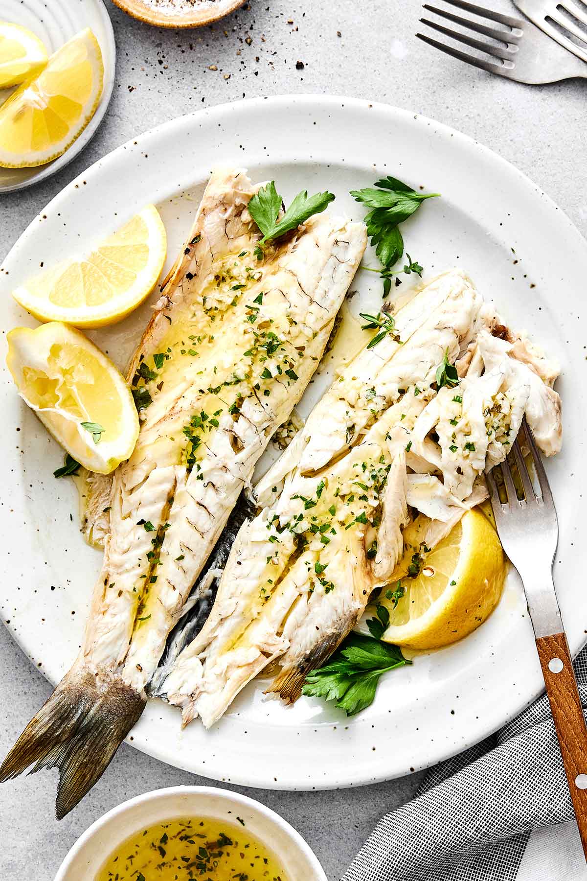 Roasted branzinos with lemon slices on a plate.