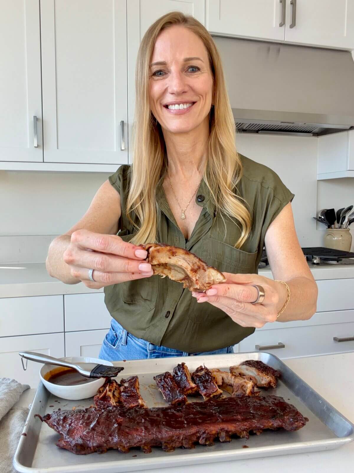 Lisa holding and eating a baby back rib.