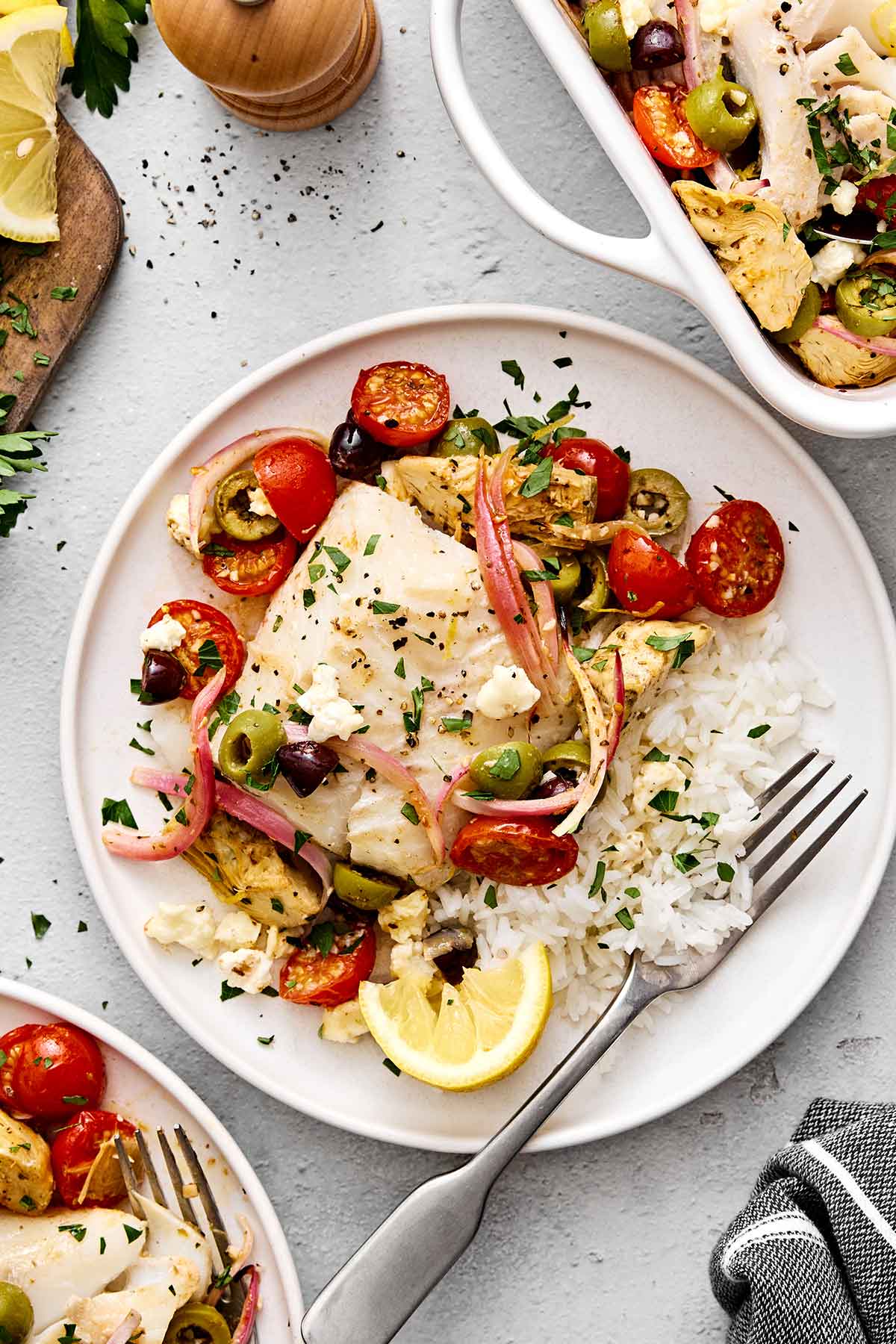 This Greek baked cod is the perfect all-in-one Mediterranean dinner! It's healthy, easy, and delicious! A plate of Greek baked cod with rice.