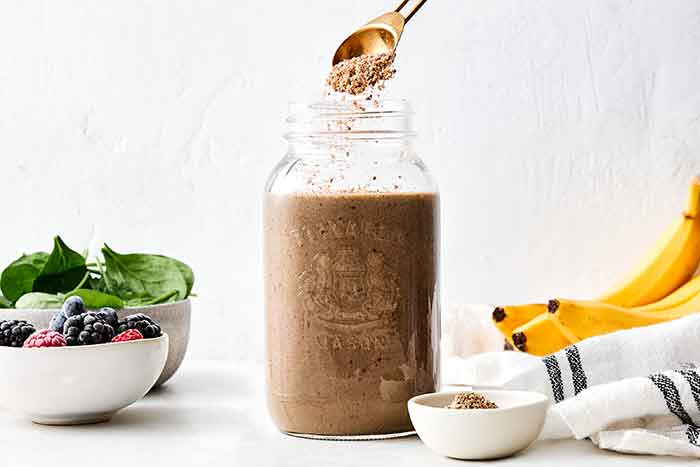 Adding flaxseed to a smoothie.