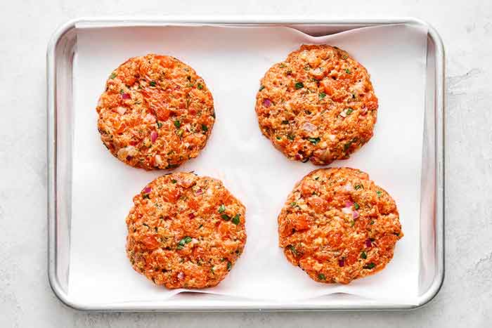Prepping salmon burgers on a sheet pan.