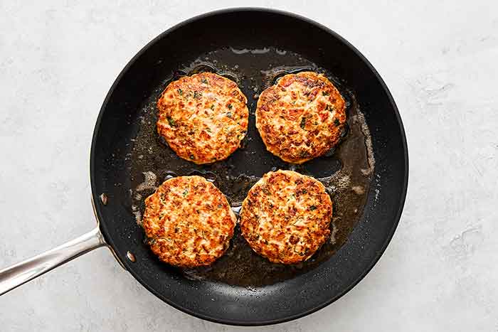 Cooking salmon burgers in a pan.