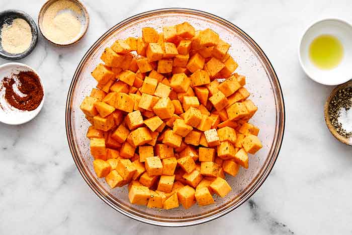 Tossing sweet potatoes in seasoning.