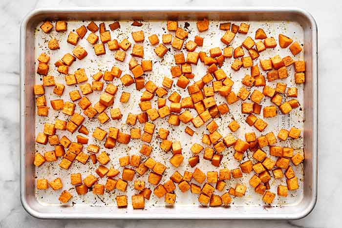 Roasted sweet potatoes on a sheet pan.