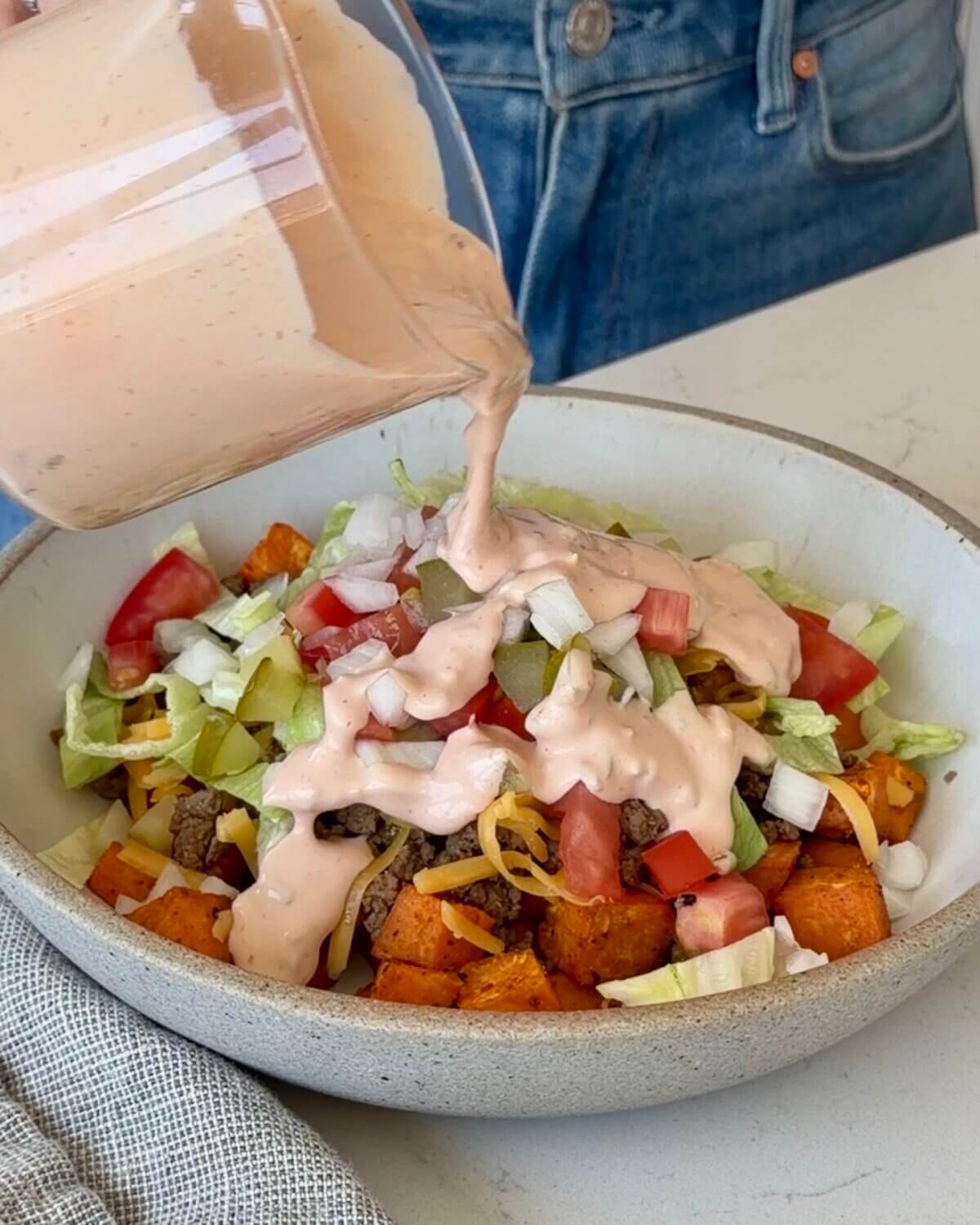 Lisa pouring the In-N-Out sauce over a burger bowl.