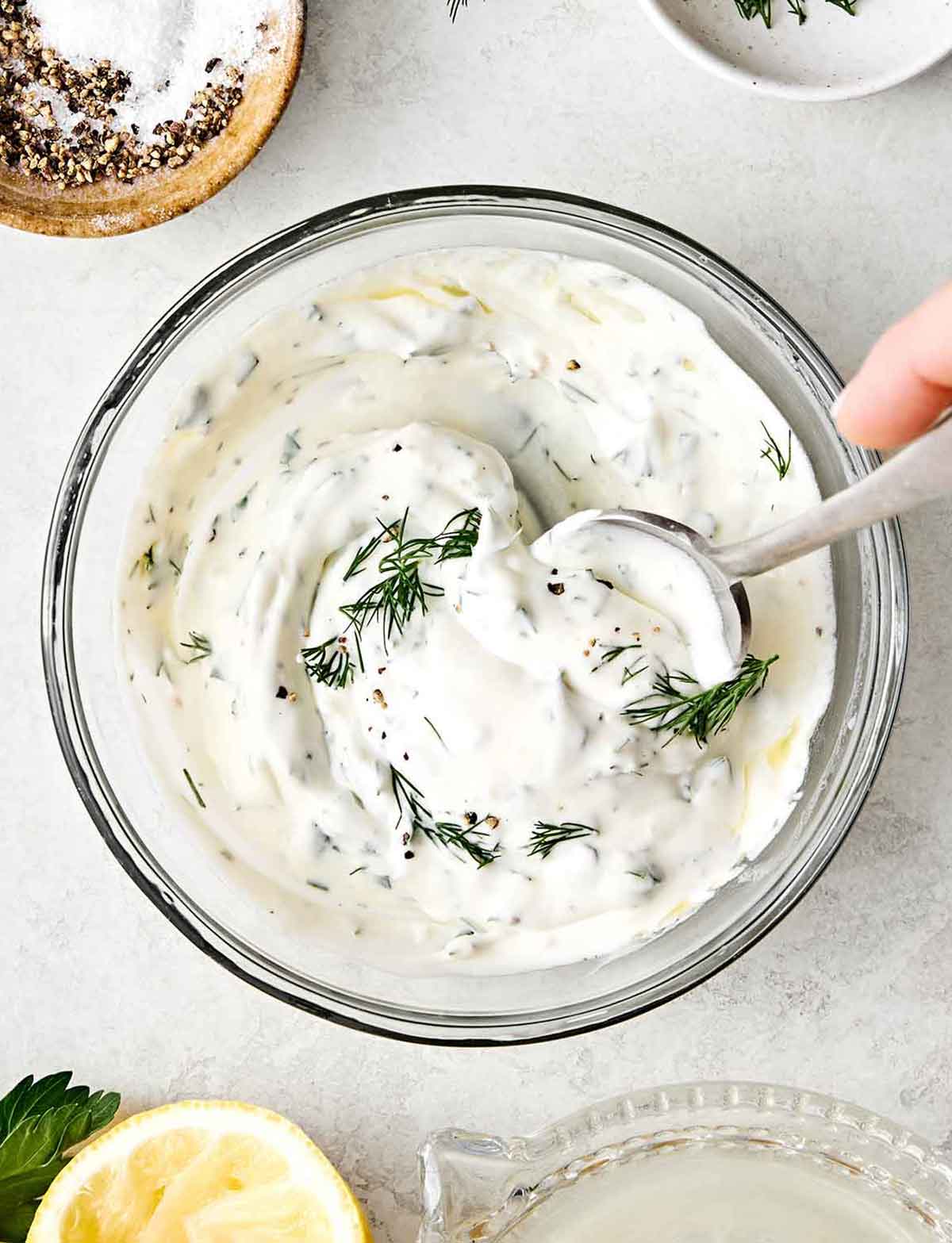 Mixing lemon dill yogurt sauce in a bowl.