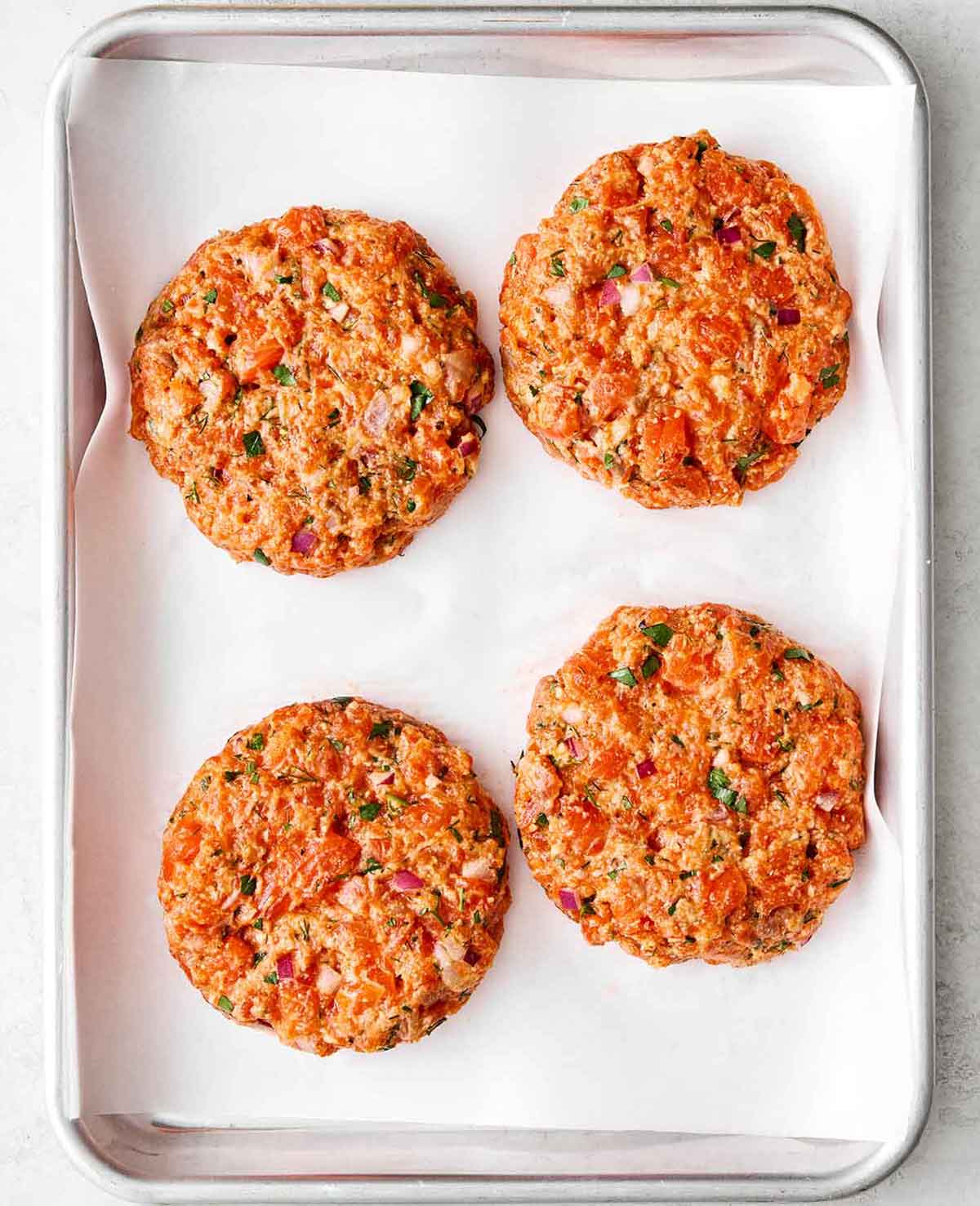 Prepping salmon burgers on a sheet pan.