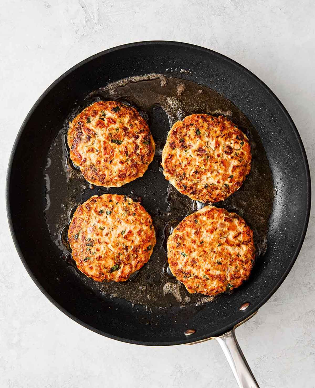 Cooking salmon burgers in a pan.