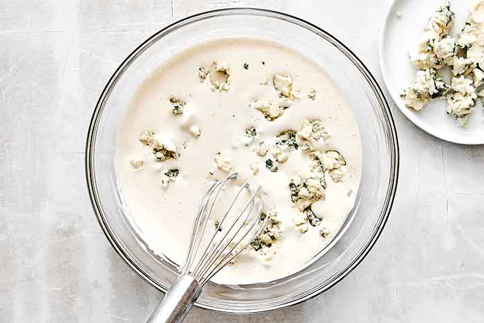 Adding blue cheese into a blue cheese dressing.
