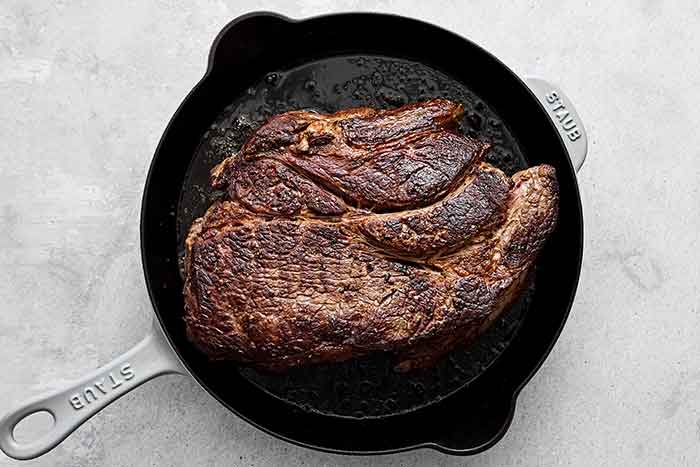 Searing chuck roast in a pan.