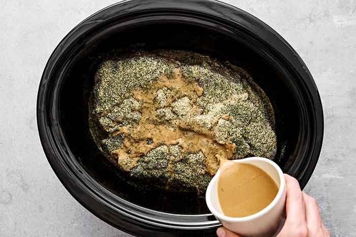 Adding liquids to chuck roast in a crockpot.