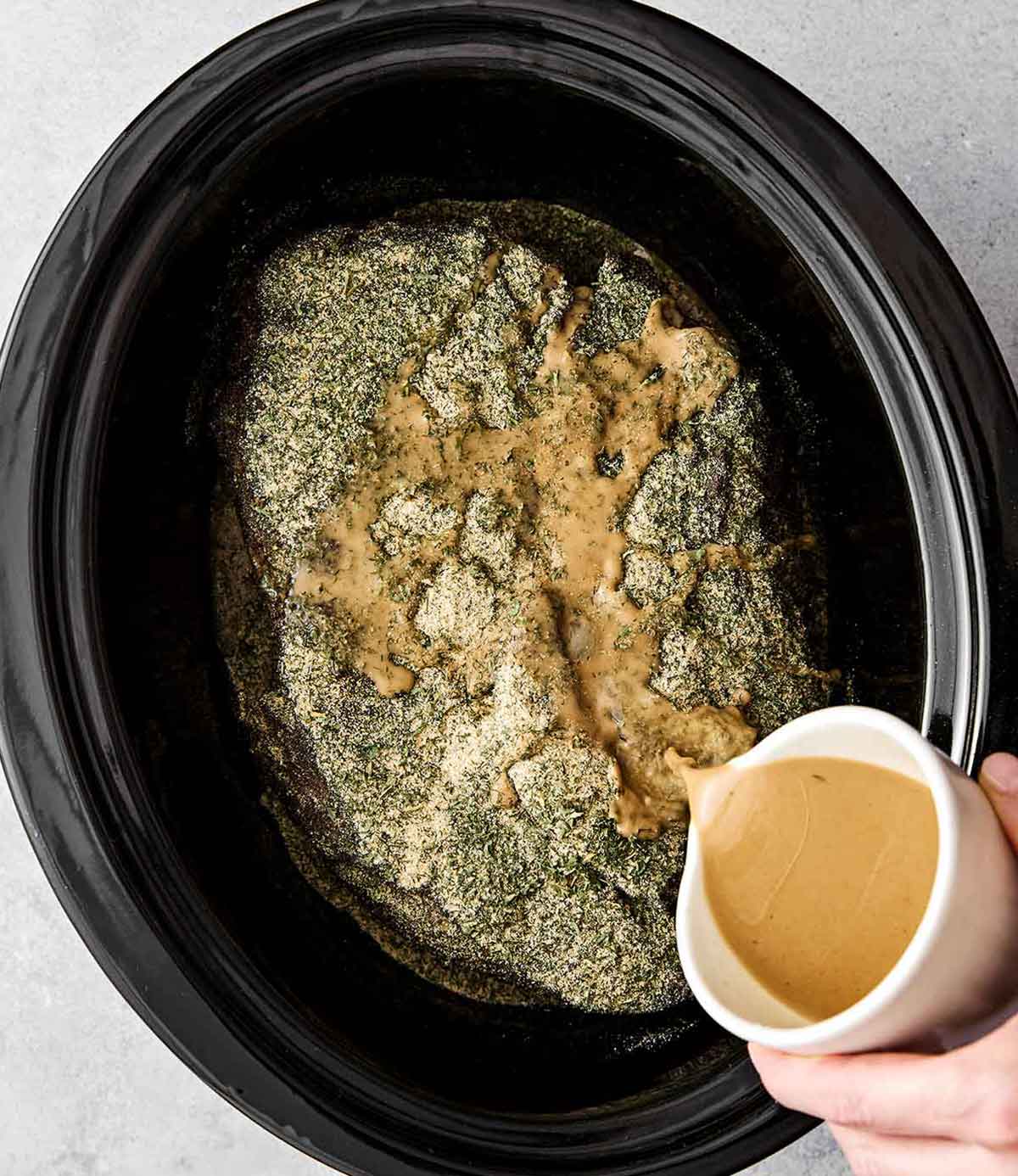 Adding liquids to chuck roast in a crockpot.