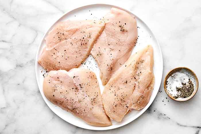 Seasoning chicken breasts.