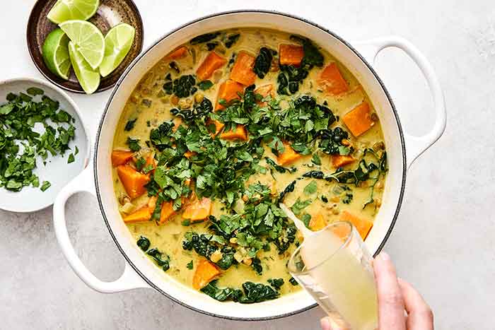 Adding lime juice to a sweet potato stew.
